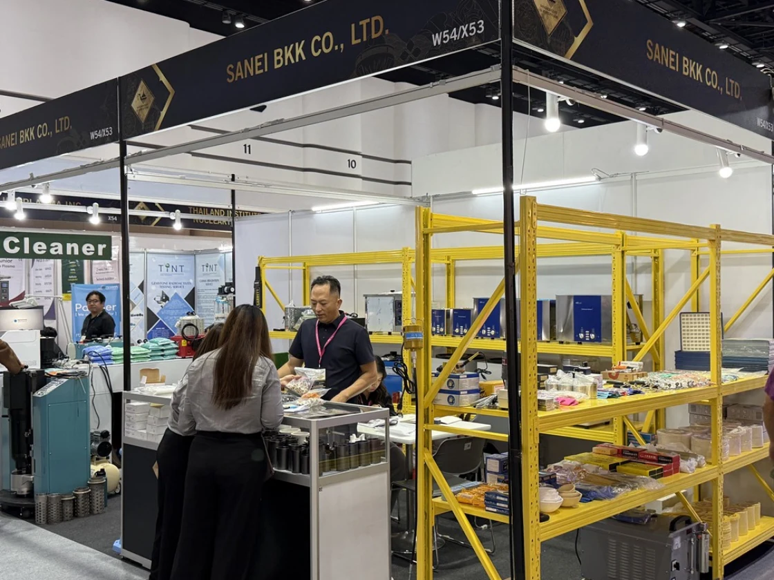 A KYG MACHINERY team member speaking with a visitor at the shared SANEI BKK exhibition booth.